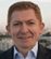 A man wearing a blue shirt and a black jacket. Description generated by AI
