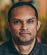 A man with a black shirt and short hair. Description generated by AI