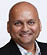 A man wearing a black suit and white shirt. Description generated by AI