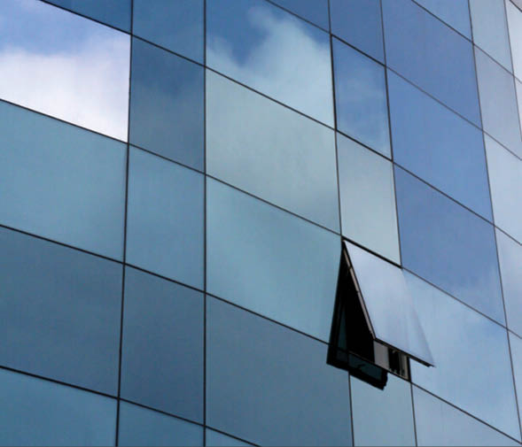 A window on a building with a cloudy sky reflected in the glass. Description generated by AI