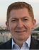 A man wearing a blue shirt and a black suit. Description generated by AI