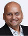 A man wearing a black suit and white shirt. Description generated by AI