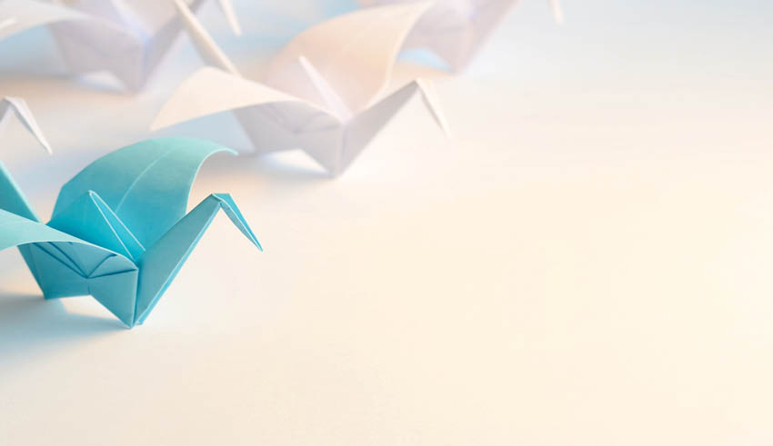 A row of origami birds are lined up on a table. Description generated by AI