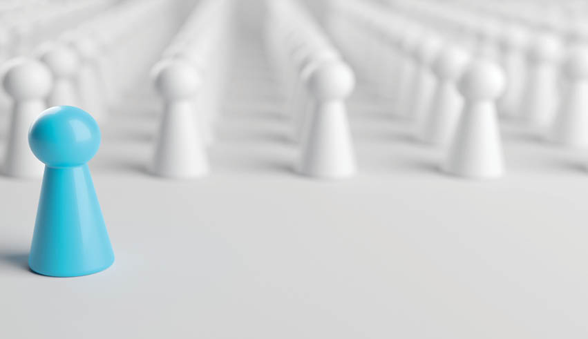 A blue toy soldier stands alone in a field of white toy soldiers. Description generated by AI